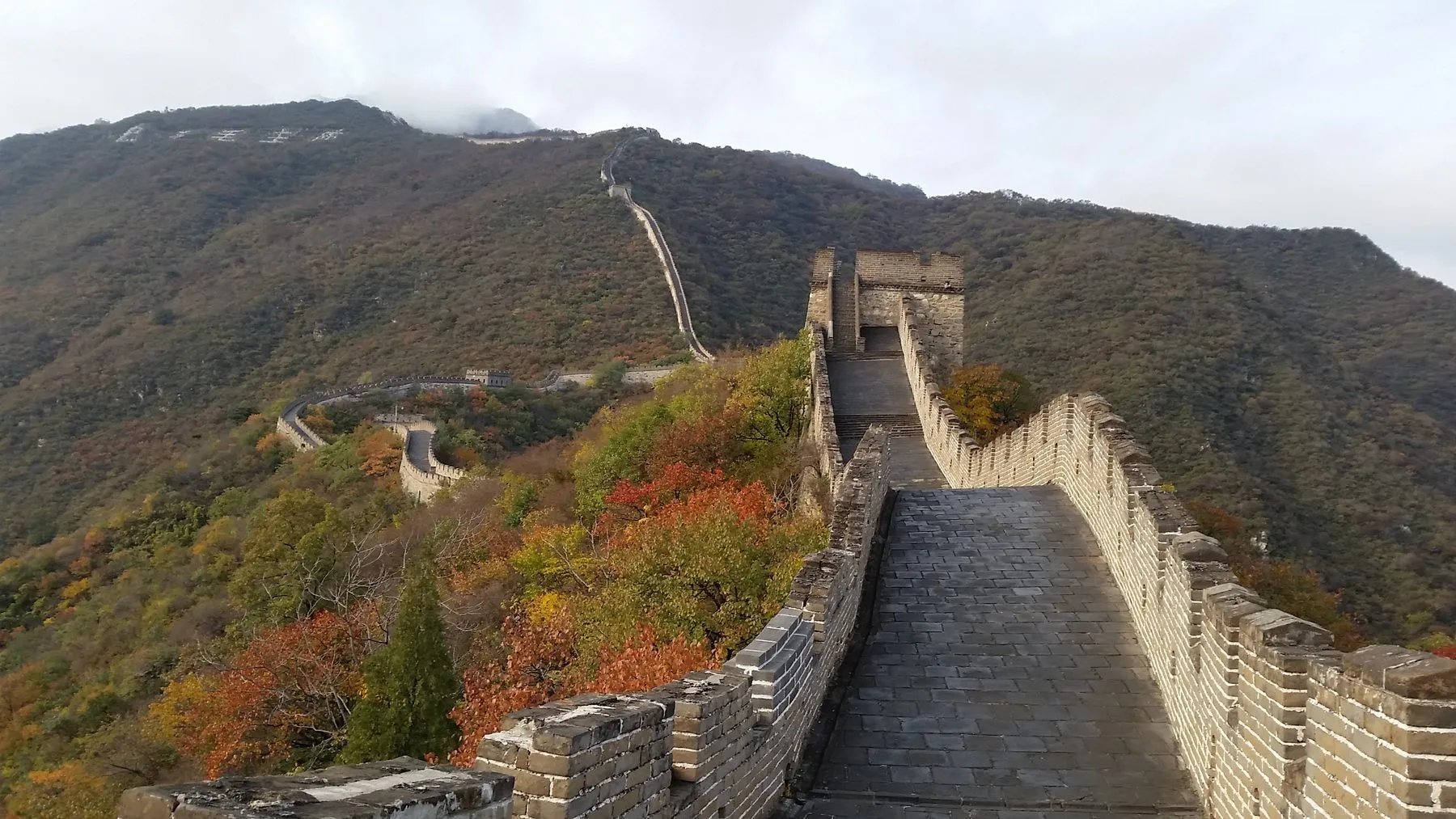 The restored Mutianyu section of the Great Wall running along a forested ridge in autumn